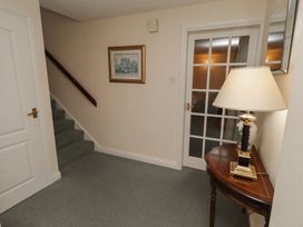 A hallway with a staircase and lamp at Grange Cottage in Belford