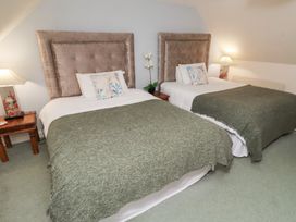 A bedroom with two beds and a lamp at Grange Cottage in Belford