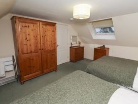 A bedroom with two beds and wooden furniture at Grange Cottage in Belford