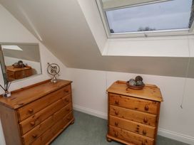 A bedroom with wooden furniture and a mirror at Grange Cottage in Belford