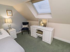A bedroom with a bed, lamp, chair, and vanity at Grange Cottage in Belford