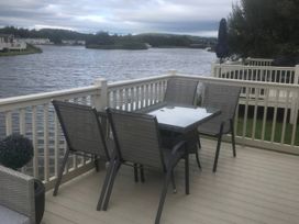 A deck with a table and chairs overlooking a river at 62 Guddlebeck, Lakeland Leisure Park, Flookburgh