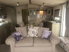 A living room with a sofa and kitchen area at 62 Guddlebeck, Lakeland Leisure Park, Flookburgh