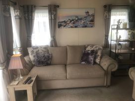 A living room with a sofa and lamp at 62 Guddlebeck in Lakeland Leisure Park, Flookburgh