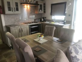 A dining room with a table and kitchen elements at 62 Guddlebeck in Lakeland Leisure Park, Flookburgh