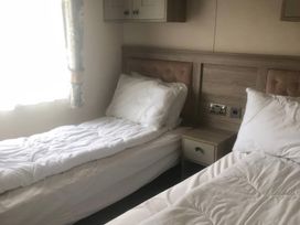 A bedroom with two beds and a bedside table at 62 Guddlebeck, Lakeland Leisure Park, Flookburgh