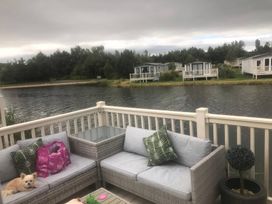 An outdoor seating area with a sofa and a lake view at 62 Guddlebeck in Lakeland Leisure Park, Flookburgh