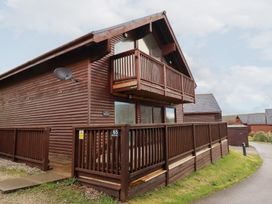 A wooden cabin with a balcony at 65 Benasa Lodge near St Columb Major
