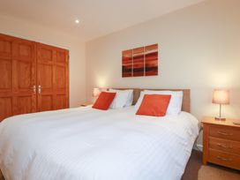 A bedroom with two beds, lamps, and artwork at 65 Benasa Lodge in Winnard's Perch near St Columb Major