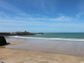 A beach with ocean waves and people at 65 Benasa Lodge, Winnard's Perch near St Columb Major