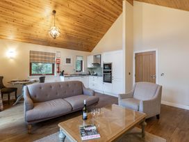 A living room with a sofa and a kitchen area at Byron Premier Spa in Dundee