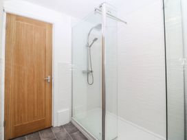 A shower with glass enclosure and wooden door at Mona Lodge in Llandudno