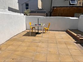 An outdoor patio with a table and yellow chairs at Mona Lodge in Llandudno