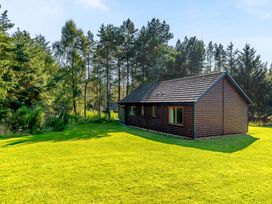 A house surrounded by trees and grass at Muirloch Spa Plus (Pet) in Dundee