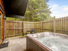 An outdoor area with a hot tub and a table with chairs at Muirloch Spa Plus (Pet) Dundee
