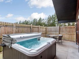 An outdoor patio with a hot tub and a table with chairs at Raeburn Premier Spa in Dundee