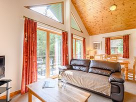 A living room featuring a sofa, a table, and large windows at Osprey Lodge in Dundee