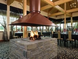 A dining room with a central fireplace and tables at Osprey Lodge in Dundee