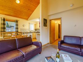 A living room with a sofa and dining area at Osprey Lodge (Pet) Dundee