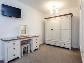 A bedroom with a television, vanity table, mirror, stool, and wardrobe at Galbraith Premier Spa (Pet) Dundee