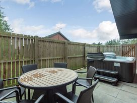 An outdoor area with a table and chairs next to a hot tub at Galbraith Premier Spa (Pet) in Dundee