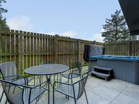 An outdoor area with a hot tub and a table with chairs at Osprey Spa Plus in Dundee