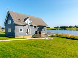 A house with a balcony by a lake at Lochside Premier Spa in Dundee