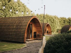 Wooden pods with tables and chairs in a garden at Garden Pod VIP Waltham