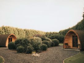 Two wooden pods in a garden with shrubs at Garden Pod VIP in Waltham