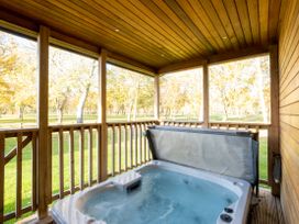 An outdoor area with a hot tub on a wooden deck at Belfry in Waltham