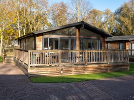A wooden cabin with a deck and trees at Belfry in Waltham