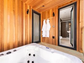 A bathroom with a hot tub and wooden walls at Dream View in Waltham