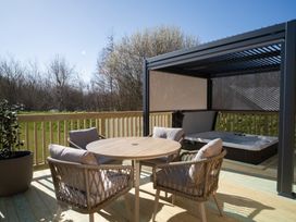 An outdoor seating area with a table and chairs beside a hot tub at The Luxury Hideaway in Waltham