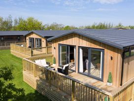 A wooden deck with chairs in front of cabins at Dovecote in Waltham