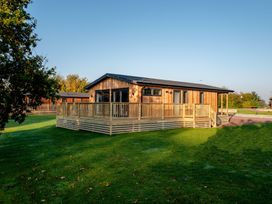 A wooden house with a deck on the grass at Dovecote in Waltham