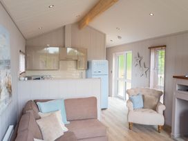 A living room with kitchen area and white chair at The Henley in Waltham