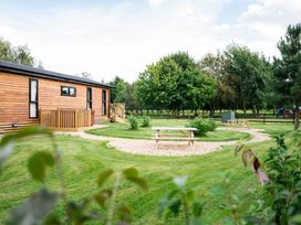 A log cabin with a deck and benches in a garden at Macosi in Waltham