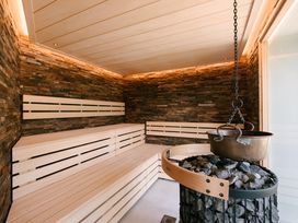 A sauna with wooden benches and a stone wall at The Luxury Retreat in Waltham