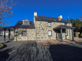 A building exterior with solar panels and gravel driveway at Ty'n Lon Pwllheli
