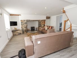 A living room with a sofa, coffee table, and television at Ty'n Lon Pwllheli