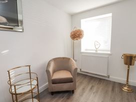 A living room with an armchair and floor lamp at Ty'n Lon Pwllheli