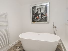 A bathroom with a bathtub and wall art at Ty'n Lon in Pwllheli