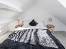 A bedroom with a bed and nightstands at Ty'n Lon in Pwllheli