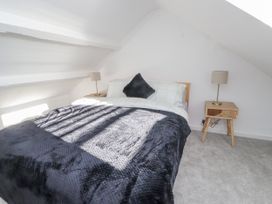 A bedroom with a bed and a bedside lamp at Ty'n Lon in Pwllheli