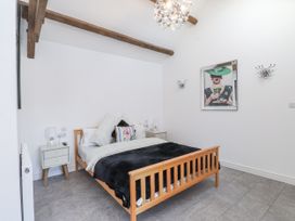 A bedroom with a wooden bed and bedside table at Ty'n Lon Pwllheli