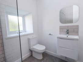 A bathroom with a toilet, sink, and mirror at Ty'n Lon in Pwllheli