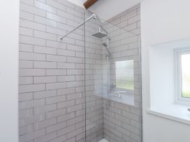 A shower with glass panel and tiles at Ty'n Lon in Pwllheli
