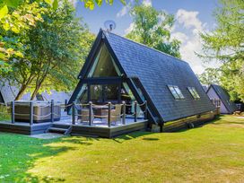 An A-frame cabin with a deck and hot tub at St Ives Studio Spa in Praze-An-Beeble