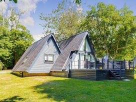 A house with a deck surrounded by trees at St Ives Lodge 3 Spa in Praze-An-Beeble