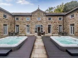 An outdoor area with two hot tubs and seating at Coach House in Praze-An-Beeble